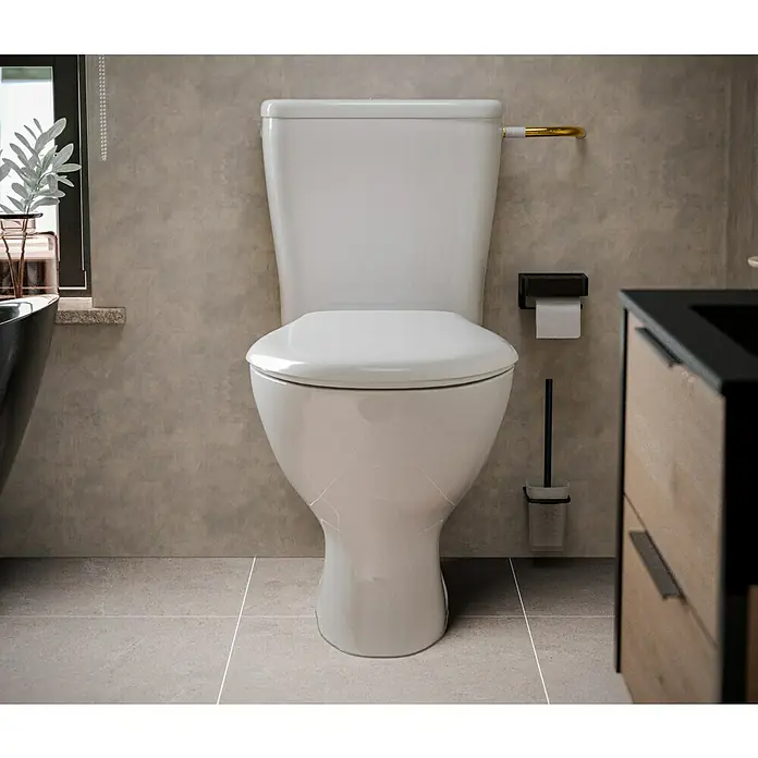 Stand-WC-Kombination Delta - Spülrandlos, Ohne Spezialglasur, Spülform: Tief, WC Abgang: Waagerecht, Weiß - Nahaufnahme einer modernen, weißen Toilette in einem stilvollen Badezimmer mit grauen Fliesen und Akzenten in Gold und Schwarz.
