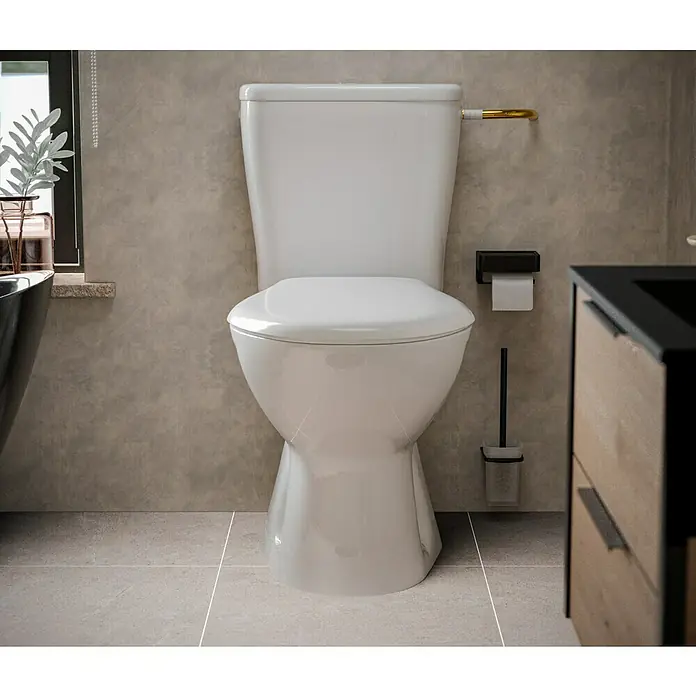 Stand-WC-Kombination Delta - Mit Spülrand, Ohne Spezialglasur, Spülform: Tief, WC Abgang: Senkrecht, Weiß - Nahaufnahme einer weißen Toilette in einem Badezimmer mit grauem Hintergrund, die die Sanitärkeramik und das Interieur hervorhebt.
