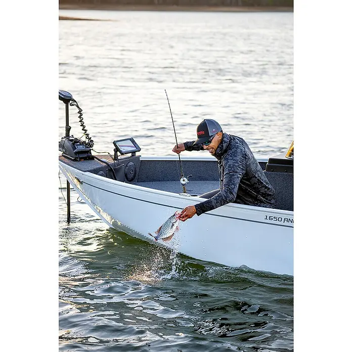 Lowrance Fishfinder & Kartenplotter Eagle 9 - Geber: TripleShot HD-Geber, 9″/229 mm IPS - Angler in einem Boot, der einen gefangenen Fisch ins Wasser zurückwirft. Das Boot ist mit moderner Angelausrüstung ausgestattet.