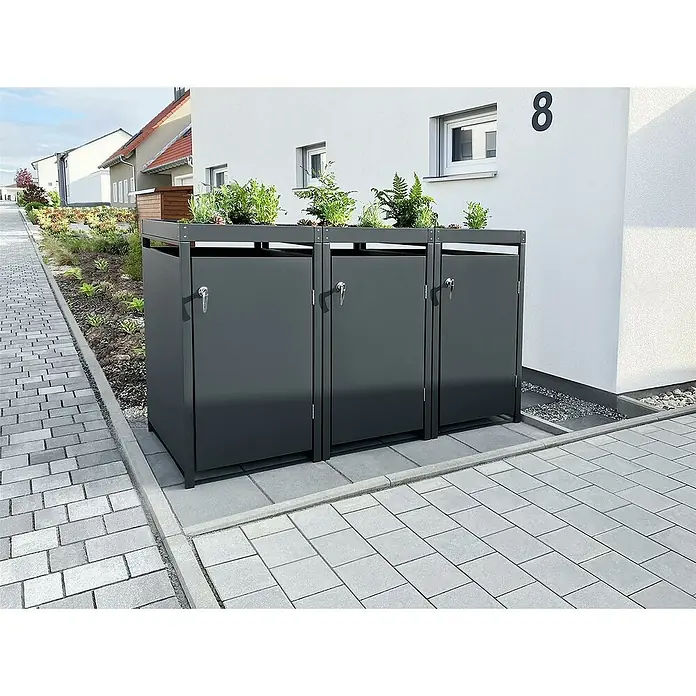 Metzler Mülltonnenbox - 198,5 x 80 cm, Stahl, Anthrazit, Geeignet für Anzahl Mülltonnen: 3 Stk., Mit Pflanzdach - Drei graue Mülltonnenboxen mit Bepflanzung auf einem gepflasterten Hof vor einem weißen Gebäude mit der Nummer 8.