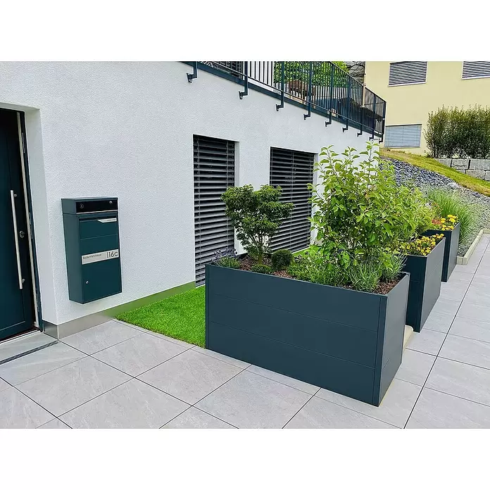 Metzler Hochbeet - 150 x 75 x 77 cm, Stahl, Anthrazit - Moderne dunkelgraue Metallpflanzkübel mit vielfältigen Pflanzen entlang einer Terrasse vor einem Gebäude.
