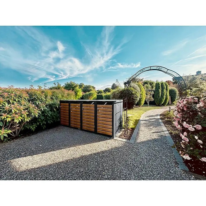 Metzler Mülltonnenbox - 272 x 80 cm, Stahl, Anthrazit/Braun, Geeignet für Anzahl Mülltonnen: 4 Stk. - Eine Mülltonnenbox aus Holz und Metall, die sich harmonisch in einen gepflegten Garten mit Kiesweg und Rosenbogen einfügt.