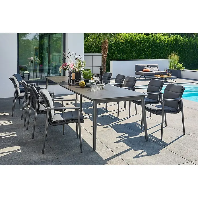 Sunfun Gartenmöbel-Set Solo Rope - 22 -tlg., Aluminium/Sintered Stone/Kunststoff/Olefin, Night-Grey, Ausziehbar - Ein eleganter Esstisch mit passenden Stühlen auf einer Terrasse. Das Set umfasst einen Tisch und acht Stühle mit grauen Polstern.