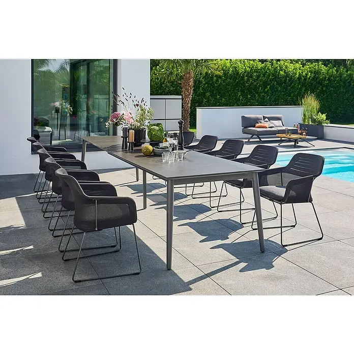 Sunfun Gartenmöbel-Set Solo - 12 -tlg., Aluminium/Sintered Stone/Polyester, Night-Grey, Ausziehbar - Ein grauer Esstisch mit passenden Stühlen steht im Freien und lädt zum Verweilen ein. Sonnenschein beleuchtet die Szene.