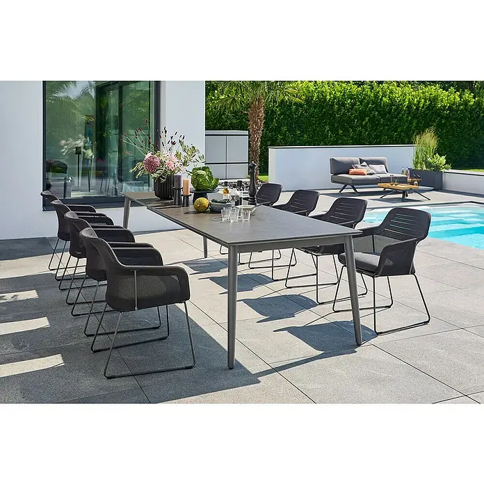 Sunfun Gartenmöbel-Set Solo - 9 -tlg., Aluminium/Sintered Stone/Polyester, Night-Grey - Grauer Esstisch mit acht Stühlen im Außenbereich neben einem Pool. Luxuriöses Gartenmöbel-Set für stilvolle Zusammenkünfte im Freien.