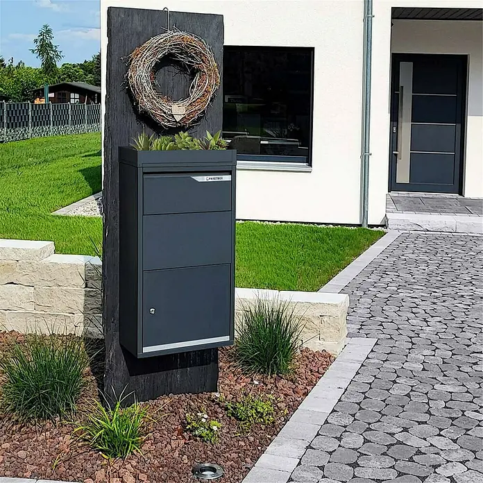 Metzler Paketbox Avalon 3 mit Pflanzdach - L x B x H: 220 x 440 x 870 mm, Anthrazitgrau, Stahl, Fassungsvermögen: 34 l - Elegantes Paketbox-System in Anthrazit, integriert in eine stilvolle Gartengestaltung mit Naturstein und dekorativem Kranz.