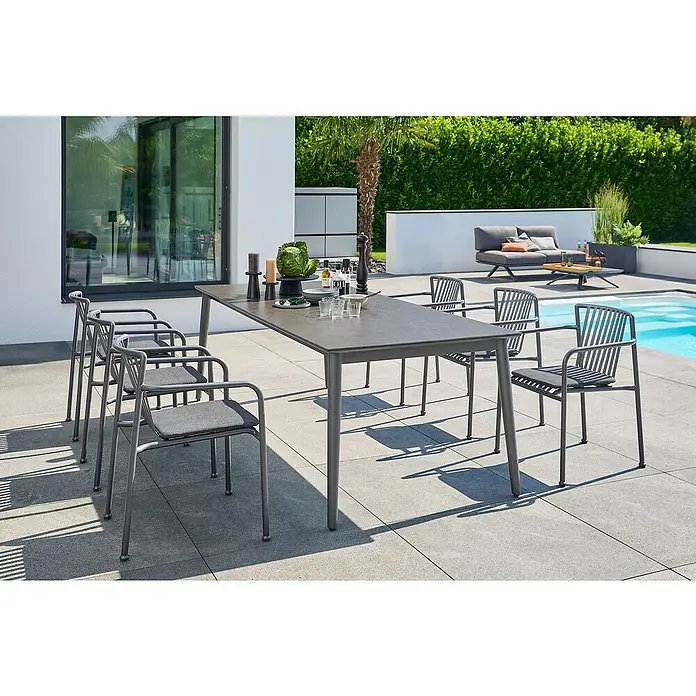 Sunfun Gartenmöbel-Set Solo/Sarah - 7 -tlg., Aluminium/Sintered Stone/Stahl, Night-Grey, Ausziehbar - Gartenszene mit einem Esstisch-Set aus grauem Metall, bestehend aus Tisch und Stühlen, ideal für Mahlzeiten im Freien.