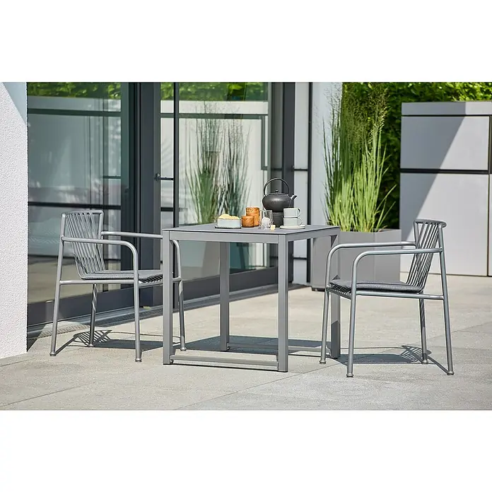 Sunfun Amy Balkontisch - L x B x H: 74 x 74 x 74 cm, Aluminium, Glas, Quadratisch, Night-Grey - Graue Terrassenmöbel: Ein Tisch mit Geschirr und zwei Stühle mit grauem Kissen laden zum Verweilen im Freien ein.