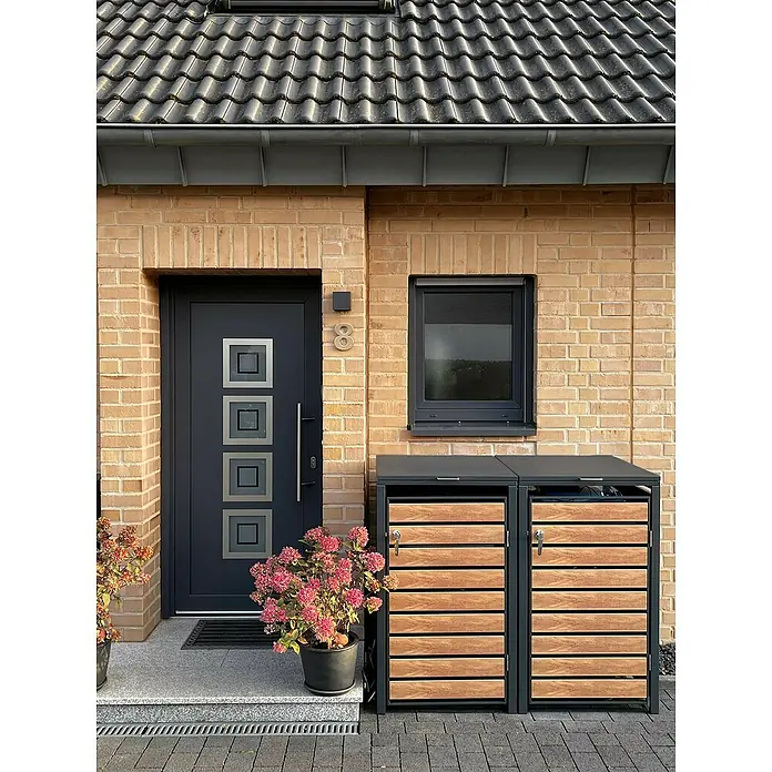 Metzler Mülltonnenbox - 136 x 80 cm, Stahl, Anthrazit/Braun, Geeignet für Anzahl Mülltonnen: 2 Stk. - Eingangsbereich eines Hauses mit modernen Mülltonnenboxen mit Holzverkleidung und grauem Rahmen, flankiert von zwei blühenden Hortensien.
