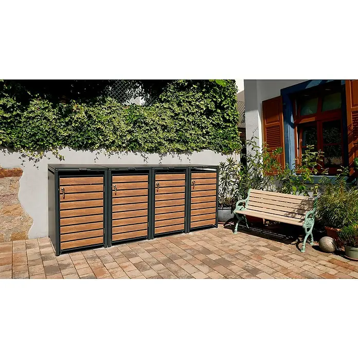 Metzler Mülltonnenbox - 272 x 80 cm, Stahl, Anthrazit/Braun, Geeignet für Anzahl Mülltonnen: 4 Stk. - Ein Mülltonnenbox-System mit drei Fächern, Holzverkleidung und grauem Rahmen, vor einer begrünten Mauer und einer Sitzbank.