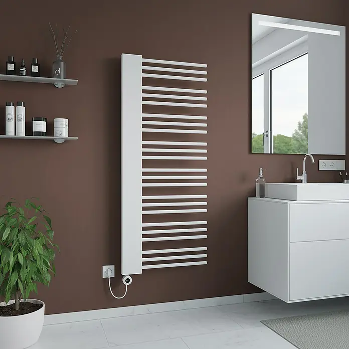 Elektro-Badheizkörper Rosi - B x H: 600 x 1.460 mm, Nennleistung: 700 W - Badezimmer-Interieur mit einem weißen Handtuchwärmer an der Wand, einem modernen Waschtisch mit Spiegel und einer Pflanze.
