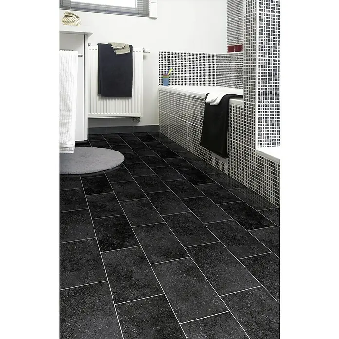Beauflor PVC-Boden Meterware Atlantic - 200 cm, Kent 909E, Schwarz - Das Bild zeigt ein modernes Badezimmer mit schwarzen Fliesen, einer Badewanne mit Mosaikfliesen und Handtüchern. Helle Fugen betonen das Fliesendesign.