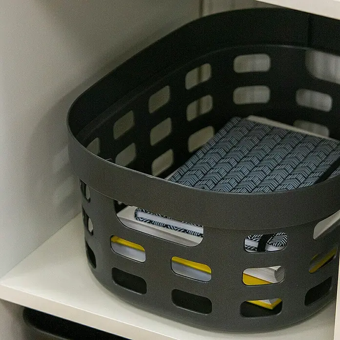 Sunware Sigma home Allzweck-Korb - L x B x H: 38 x 28 x 15,7 cm, Anthrazit, Kunststoff - Ein grauer Korb mit Aussparungen steht in einem Schrank und beinhaltet Bücher und eine Notizbuch.