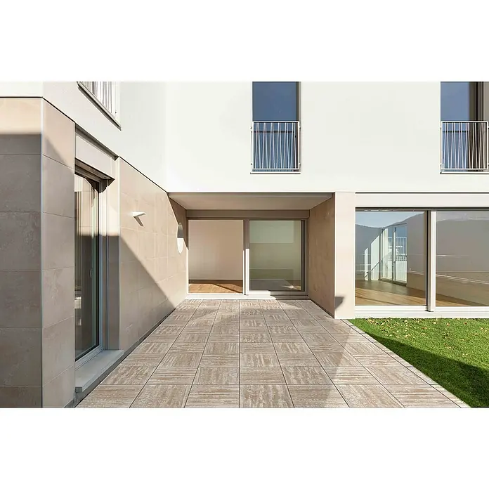 Terrassenplatte Saturn - 50 x 50 x 4 cm, Tundra, Beton - Außenansicht eines modernen Gebäudes mit einer gefliesten Terrasse und großen Schiebetüren, die einen hellen, minimalistischen Innenraum zeigen.