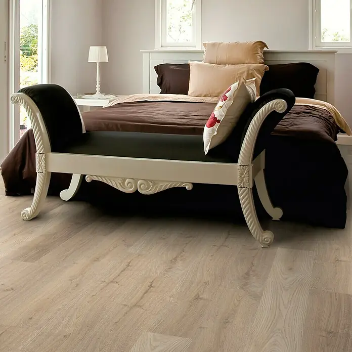 Decolife Vinylboden Comfort - Hardy Oak, Landhausdiele, 1.220 x 185 x 10,5 mm - Elegante Chaiselongue in Schwarz und Weiß vor einem stilvollen Schlafzimmer mit Holzboden, die das luxuriöse Ambiente hervorhebt.