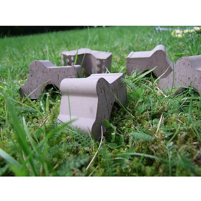 Terrakottafuß Set - Höhe: 4,2 cm, Naturmaterialien, Basalt, 3 Stk. - Steine mit besonderer Form liegen im Gras. Diese geformten Steine sind Dekorationselemente für den Garten und fügen sich gut in die Natur ein.