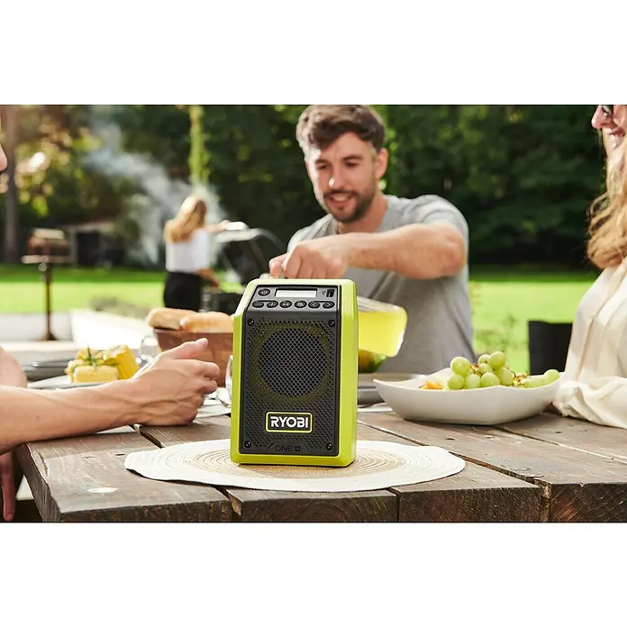 Ryobi ONE+ Akku-Bluetooth-Radio RRDAB18-0 - 10 W, Ohne Akku - Ein Ryobi ONE+ Radio, ein vielseitiges und robustes Audiogerät, ideal für Baustellen oder Outdoor-Aktivitäten, steht auf einem Holztisch.
