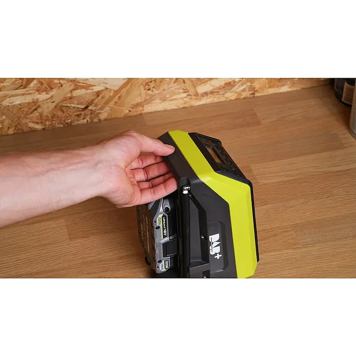 Ryobi ONE+ Akku-Bluetooth-Radio RRDAB18-0 - 10 W, Ohne Akku - Ein Ryobi DAB+ Radio mit einem Akku wird von einer Hand gehalten. Das Radio ist grün und schwarz.
