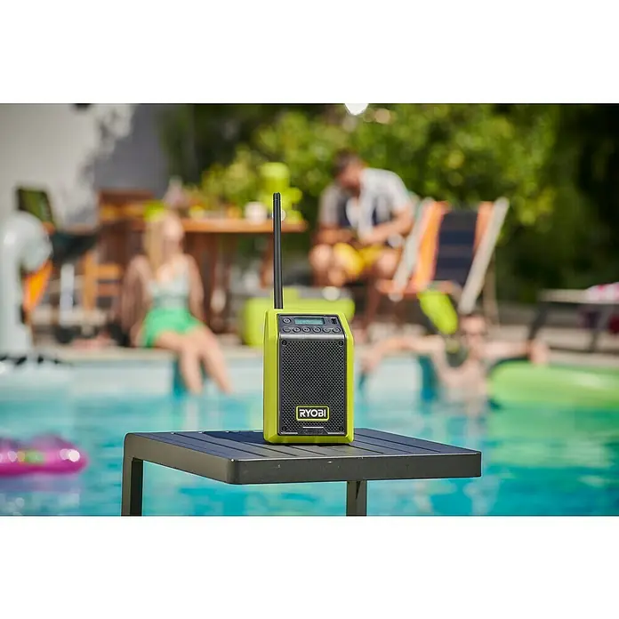 Ryobi ONE+ Akku-Bluetooth-Radio RRDAB18-0 - 10 W, Ohne Akku - Das Ryobi Radio steht auf einem Tisch am Pool, während Menschen sich im Hintergrund entspannen.