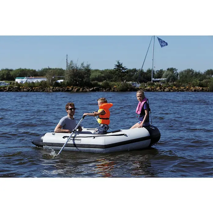 Talamex Schlauchboot Luftboden Aqualine QLA250 - L x B: 250 x 152 cm, Tragkraft: 400 kg, Geeignet für: 2+1 Personen - Ein Aquamex Schlauchboot mit einem Mann und zwei Kindern darauf, die auf dem Wasser rudern und Schwimmwesten tragen.