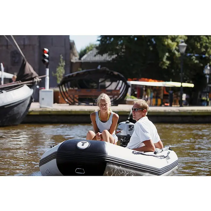 Talamex Schlauchboot Aluminiumboden Aqualine QLX270 - L x B: 270 x 152 cm, Tragkraft: 410 kg, Geeignet für: 3 Personen - Ein kleines Schlauchboot mit einem Mariner-Motor auf einem Kanal, in dem ein Mann und eine junge Frau sitzen. Es bietet eine entspannte Wasserfahrt.
