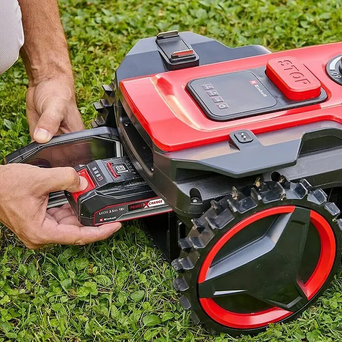 Einhell Power X-Change 18V Mähroboter Freelexo 500 - 500 m², Schnittbreite: 18 cm, Induktionsgestützte Navigation, Begrenzungskabel - Ein Mann setzt einen Einhell Power X-Change Akku in einen Einhell Mähroboter ein. Der Akku ist rot und schwarz.