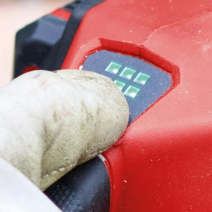 Einhell Professional PXC 18V Akku-Kettensäge GP-LC 36/40 - 36 V, Li-Ionen, Ohne Akku, Schwertlänge: 40 cm - Nahaufnahme eines roten Akkuschraubers mit einer Hand, die einen Knopf mit grünen LED-Anzeigen drückt.