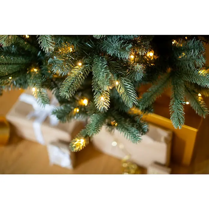 Evergreen Künstlicher Weihnachtsbaum Vermont Fichte - Höhe: 210 cm, Grün, LED-Beleuchtung - Weihnachtsbaum mit Lichtern und Geschenken. Die Geschenke sind in braunes Papier gewickelt und mit weißen Schleifen verziert, für eine festliche Stimmung.
