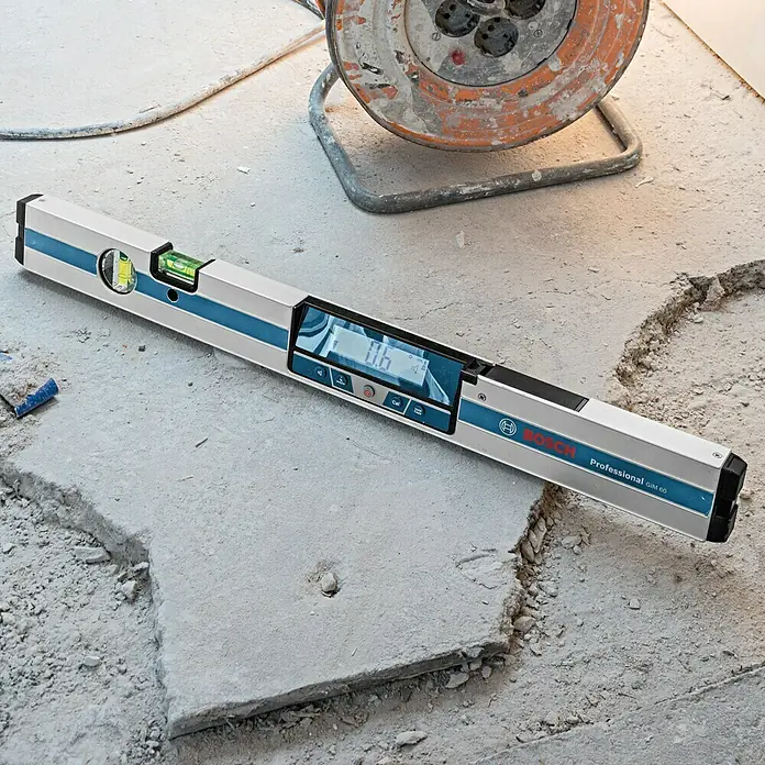 Bosch Professional Digitale Wasserwaage GIM 60 - 600 mm, Messbereich: 0 ° - 360 ° (4 x 90 °) - Ein Bosch Professional GIM 60 Digital-Neigungsmesser auf einer unebenen Betonfläche, ideal für präzise Messungen im Bauwesen.