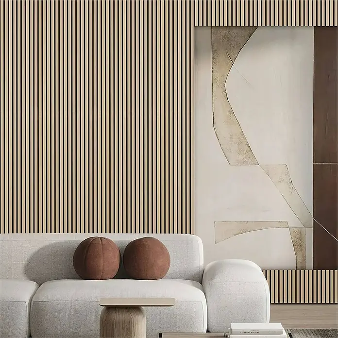 Sonido Akustikpaneel Elements - New Oak Light, L x B x S: 2.440 x 560 x 18 mm - Stilvolles Wohnzimmerdesign mit hellem Sofa, dekorativen Kissen und einer Wand mit Holzpaneelen, ergänzt durch ein abstraktes Kunstwerk.