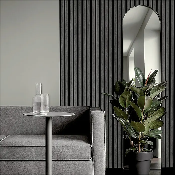 Sonido Akustikpaneel Elements - Black Oak, L x B x S: 1.200 x 560 x 18 mm - Elegantes Wohnzimmer mit grauem Sofa, Beistelltisch mit Glasgefäßen, Spiegel und einer Zimmerpflanze vor einer Wand mit Holzpaneelen.