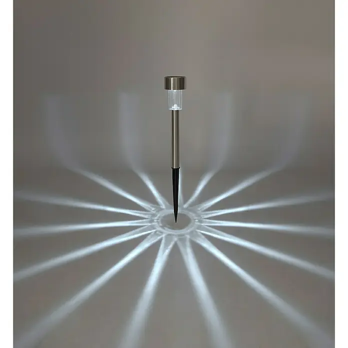 Solarleuchten-Set - Edelstahl, IP44 - Nahaufnahme einer einzelnen Solar-Gartenleuchte, die ein sternförmiges Lichtmuster auf den Boden wirft. Perfekt für stimmungsvolle Beleuchtung.