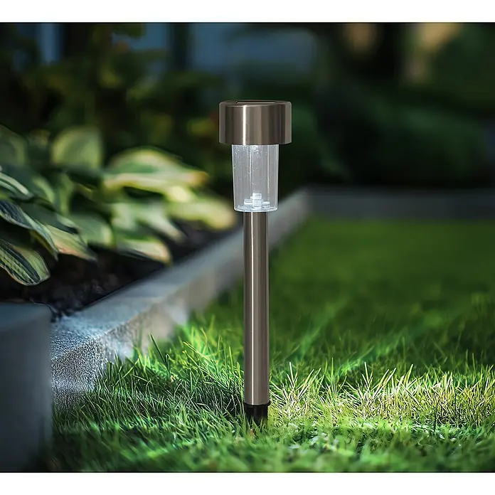Solarleuchten-Set - Edelstahl, IP44 - Nahaufnahme einer einzelnen Solarleuchte aus Metall, die in einem Garten in grünes Gras gesteckt wurde.