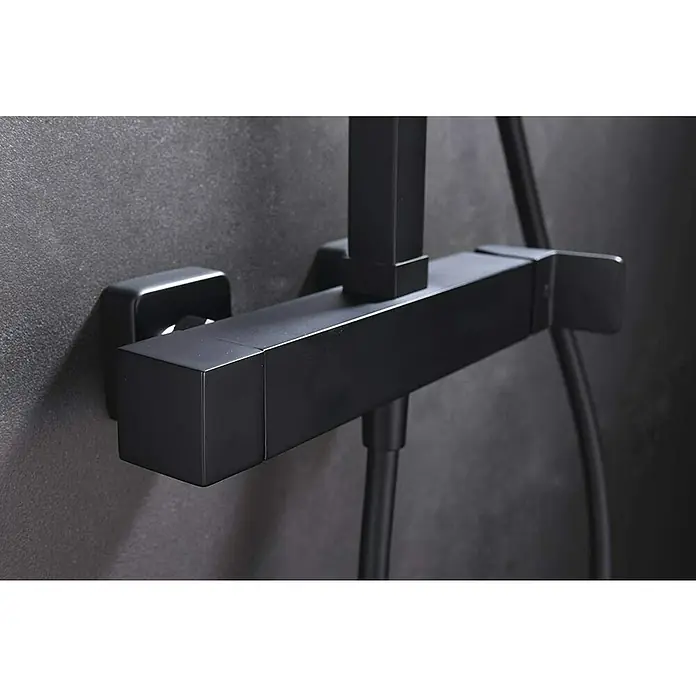 Imex Fiyi Sistema de ducha - Con grifo monomando, Negro - Primer plano de un grifo de ducha negro y cuadrado montado en una pared gris. El diseño moderno es minimalista y elegante.