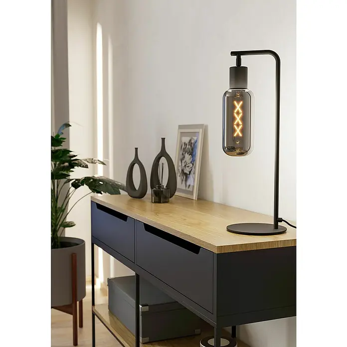 Eglo LED-Tischleuchte Maione - L x B x H: 17 x 9 x 50,5 cm, E27, Leistung je Leuchtmittel: 4 W - Elegante Tischleuchte mit dekorativer Glühbirne auf einem modernen Konsolentisch mit Holzplatte und dunklen Schubladen.