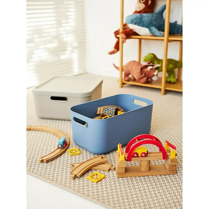 Rotho Aufbewahrungsbox - L x B x H: 39,5 x 23,5 x 17,7 cm, Kunststoff, Horizonblau, 12 l - Das Bild zeigt zwei Aufbewahrungsboxen, eine blaue Box mit Spielzeug und eine graue Box mit Deckel, die im Kinderzimmer stehen.