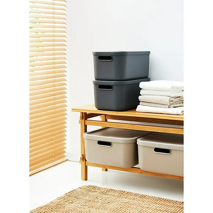 Rotho Aufbewahrungsbox - L x B x H: 39,5 x 35,5 x 17,7 cm, Kunststoff, Anthrazit, 20 l - Auf einem Regal gestapelte Aufbewahrungsboxen in Grau und Beige, daneben gefaltete Handtücher. Ideal für Ordnung im Haus.