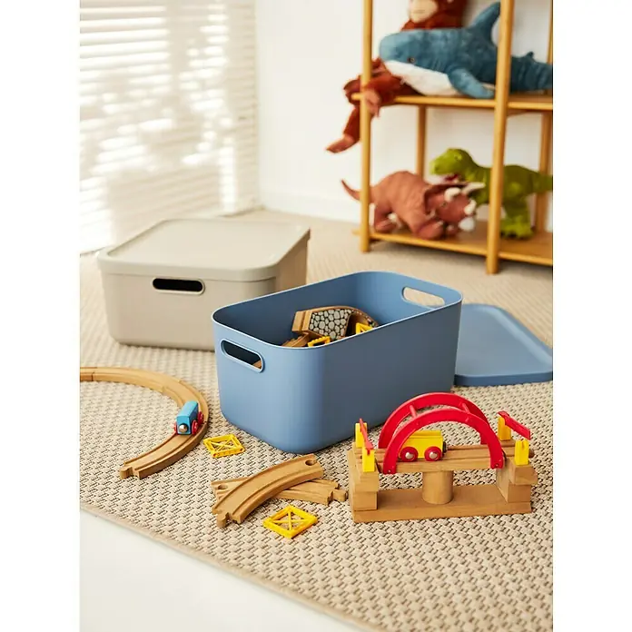 Rotho Aufbewahrungsbox - L x B x H: 39,2 x 35,5 x 17,7 cm, Kunststoff, Cappuccino, 20 l - Ein Arrangement aus Spielzeugaufbewahrungsboxen mit Deckel in Beige und Blau, sowie Holzspielzeug auf einem gemusterten Teppich.