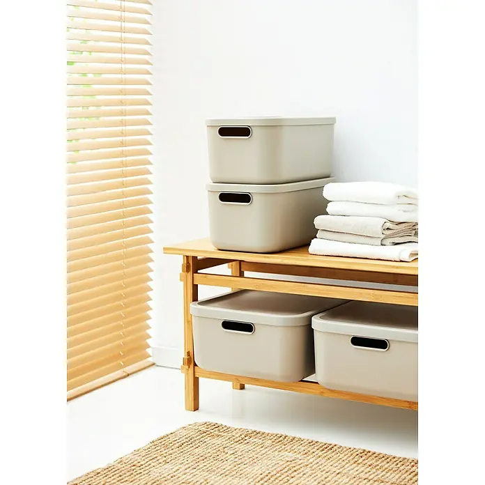 Rotho Aufbewahrungsbox - L x B x H: 39,5 x 23,5 x 17,7 cm, Kunststoff, Cappuccino, 12 l - Auf dem Holzregal stehen graue Aufbewahrungsboxen mit Deckel und Griffen, daneben liegen gefaltete Handtücher.