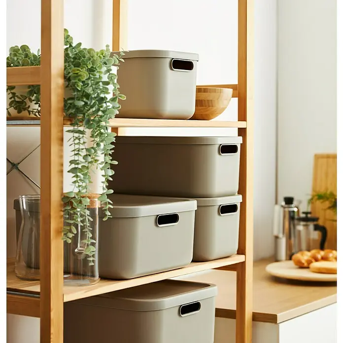Rotho Aufbewahrungsbox - L x B x H: 39,5 x 23,5 x 17,7 cm, Kunststoff, Cappuccino, 12 l - Mehrere graue Aufbewahrungsboxen mit Deckel und Griffen, gestapelt auf einem Holzregal, ideal für die Organisation von Küchenutensilien.