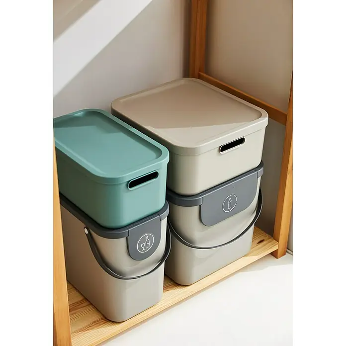 Rotho Aufbewahrungsbox - L x B x H: 39,2 x 23,5 x 17,7 cm, Kunststoff, Mistelzweiggrün, 12 l - Zwei modulare Abfallbehälter mit Deckel und Griffen aus Kunststoff in Beige und Grün gestapelt im Regal.