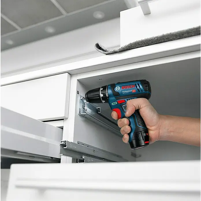 Bosch Professional Akku-Bohrschrauber GSR 12V-15 - 12 V, Ohne Akku, 30 Nm - Nahaufnahme eines Bosch Professional Akku-Bohrschraubers beim Einsatz in einem weißen Möbelstück. Das Gerät besticht durch seine blaue Farbgebung.