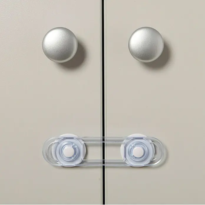Dreambaby Mini-Multifunktionsverschluss - Kleben, Farblos, 4 Stk. - Nahaufnahme einer Kindersicherung an einem grauen Schrank mit zwei runden, silbernen Knöpfen. Sicherer Haushalt mit Kindersicherungen.