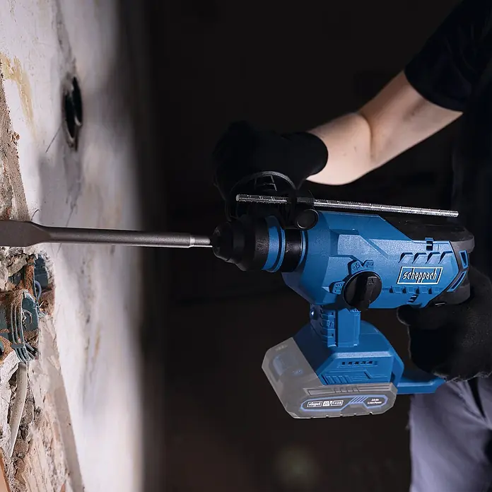 Scheppach IXES 20V Akku-Bohrhammer BC-RHD230-X - 20 V, 2,2 J, Bohrfutter/Werkzeugaufnahme Elektromaschine: SDS-Plus-Aufnahme, Max. Schlagzahl: 5.500 /min - Nahaufnahme eines blauen Scheppach Abbruchhammers in Aktion, der eine Wand aufbricht.