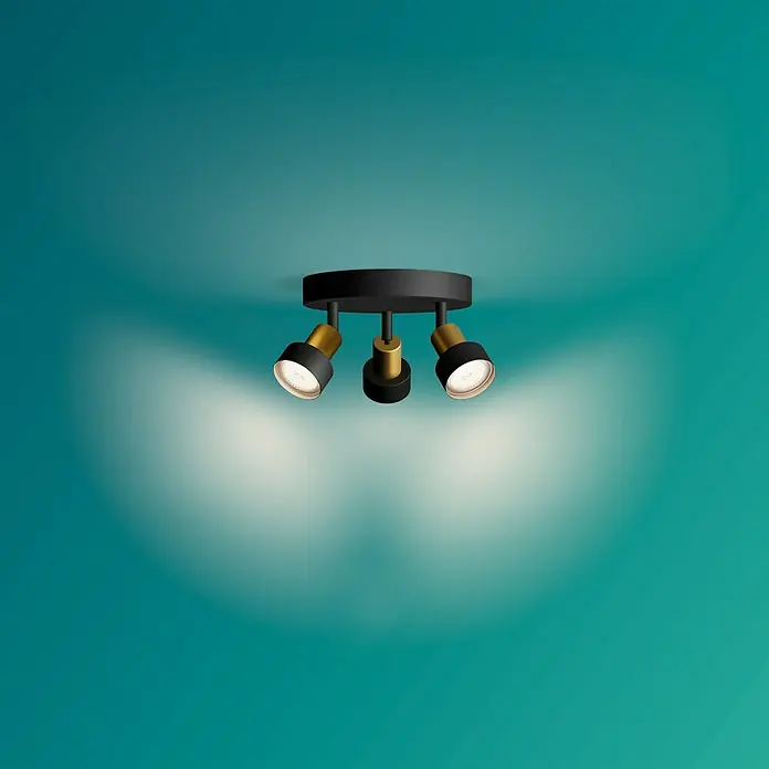 Philips Regleta Conduit - 5 W, L x An x Al: 22 x 20 x 9 cm, Negro, GU10 - Esta imagen muestra una elegante lámpara de techo con tres focos en negro y dorado. La lámpara llama la atención y proporciona una luz fantástica.