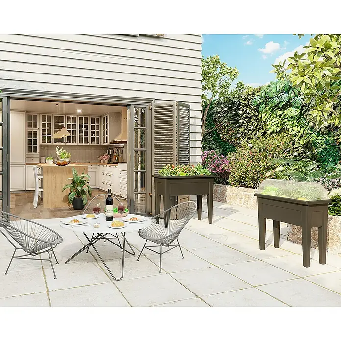 Artevasi Venezia Hochbeet - L x B x H: 80 x 39 x 69 cm, Kunststoff, Grün - Gartenbild mit erhöhten Pflanzkästen. Ideal für den Anbau von Gemüse und Kräutern im Freien, mit einer Küche im Hintergrund.