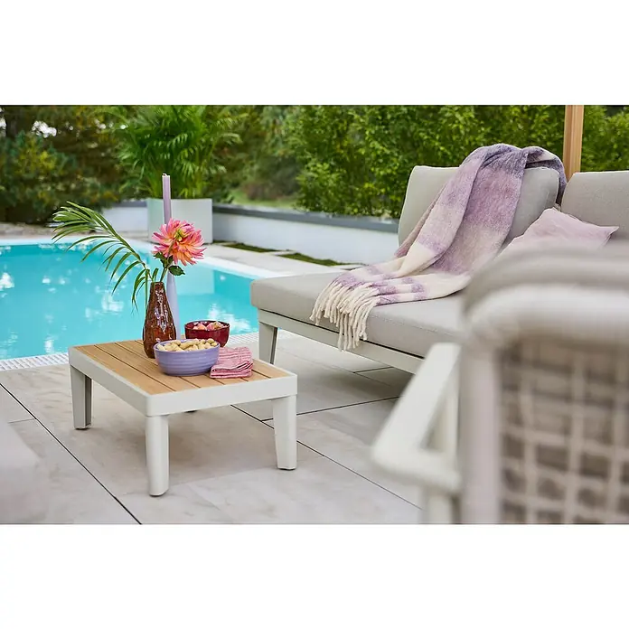 Sunfun Solo Garten-Couchtisch - L x B x H: 72 x 41,5 x 26 cm, Light-Greige - Stylischer Loungebereich im Freien mit eleganten Möbeln, darunter ein einladendes Sofa mit Überwurf und Beistelltisch.
