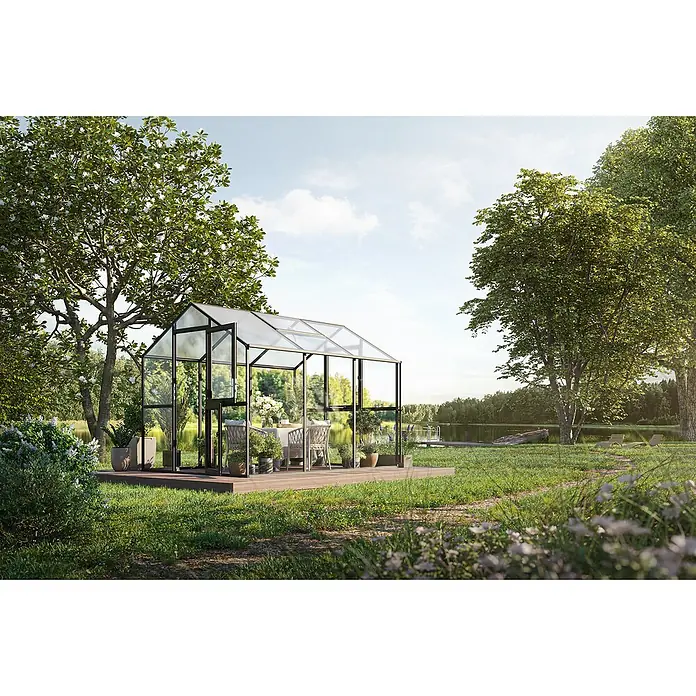 KGT Gewächshaus Aptasia III - Außenmaß inkl. Dachüberstand (B x T): 233 x 323 cm, Material Seitenwand: Glas, 4 mm, Anthrazit-Grau - Ein Gewächshaus aus Glas und Metall steht auf einer Holzterrasse im Garten. Im Inneren befindet sich ein Esstisch mit Stühlen.