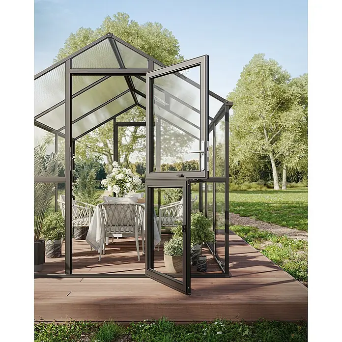 KGT Gewächshaus Aptasia IV - Außenmaß inkl. Dachüberstand (B x T): 233 x 429 cm, 4 mm, Anthrazit-Grau - Elegantes Gewächshaus mit geöffneter Tür, das eine gemütliche Essecke umrahmt. Einladende Gartenoase für stilvolle Entspannung im Grünen.