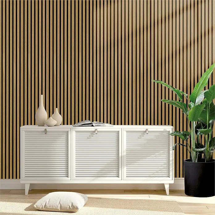 Sonido Akustikpaneel Elements - Oiled Oak, L x B x S: 1.200 x 560 x 18 mm - Eine elegante Wohnzimmereinrichtung mit einem weißen Sideboard vor einer Akzentwand mit Holzlatten. Dekorative Vasen und eine Zimmerpflanze verschönern den Raum.